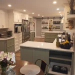 Kitchen with dark green island, white cabinets and floral centerpiece