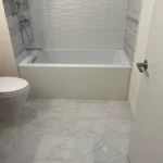 Bathroom with soaking tub, toilet, and tile flooring
