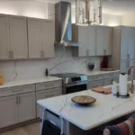 White kitchen with stainless range hood, marble counters and pendant lighting