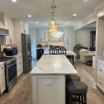 White kitchen with waterfall marble island, pendant lighting, and bar seating