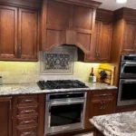 Wood cabinetry kitchen with granite backsplash and under-cabinet lighting