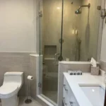 Glass shower enclosure with marble tile