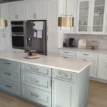 Sage green kitchen with brass hardware and marble countertops