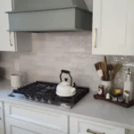 White kitchen with marble backsplash and gas cooktop