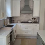 White kitchen with marble backsplash and farmhouse sink