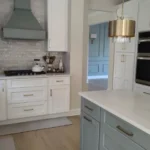 Sage green kitchen with marble counters and built-in microwave