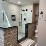 Marble shower with dark brick accent wall and black hardware