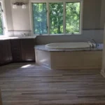 Corner tub near windows with wood look flooring