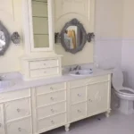 White vanity with oval mirror and toilet