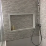 Tile shower wall with handheld showerhead and niche