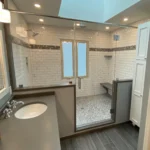 Bathroom with glass shower, vanity, and skylight