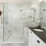 Glass shower enclosure with marble tile surround