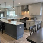 Dark navy kitchen island with white cabinets and pendant lighting