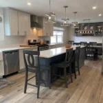 Kitchen with dark island, bar seating and wood flooring