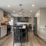 White kitchen with dark wood dining table and pendant lighting