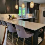 Dark kitchen island with gold pendant lighting and bar stools