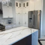 White kitchen with waterfall marble island and stainless refrigerator