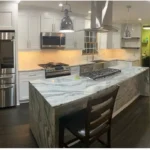 Kitchen with veined marble waterfall island and gold hardware