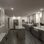 Two-tone gray kitchen with long island and wood flooring