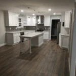 White kitchen with center island and dark wood flooring