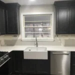 Dark kitchen with farmhouse sink and glass-front cabinet