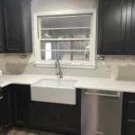 Dark kitchen with farmhouse sink below a window