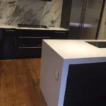 White waterfall island in a dark wood-floored kitchen