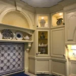 Cream cabinetry with decorative tile inset and glass-front doors