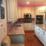 Kitchen with pink accent wall and dark cabinetry