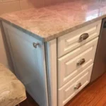 Close-up of white cabinetry with marble waterfall island edge