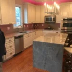 Kitchen with marble waterfall island and stainless appliances