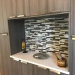 Kitchen niche with mosaic tile backsplash and wood shelving