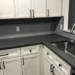 White kitchen with dark countertops and tile backsplash