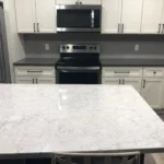 White kitchen with marble countertops and stainless range