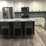 White kitchen with island seating and dark flooring