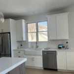 White kitchen with stainless steel appliances and window above the sink