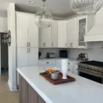 White kitchen with marble island, wood accents and hanging pendant lights