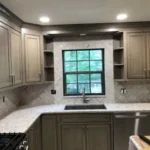Sage green and white kitchen with window above the sink