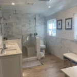 Marble tile shower with glass enclosure and bench